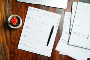 a wooden table topped with papers and a pen