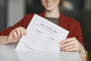 Smiling woman holds an election ballot paper during voting day.